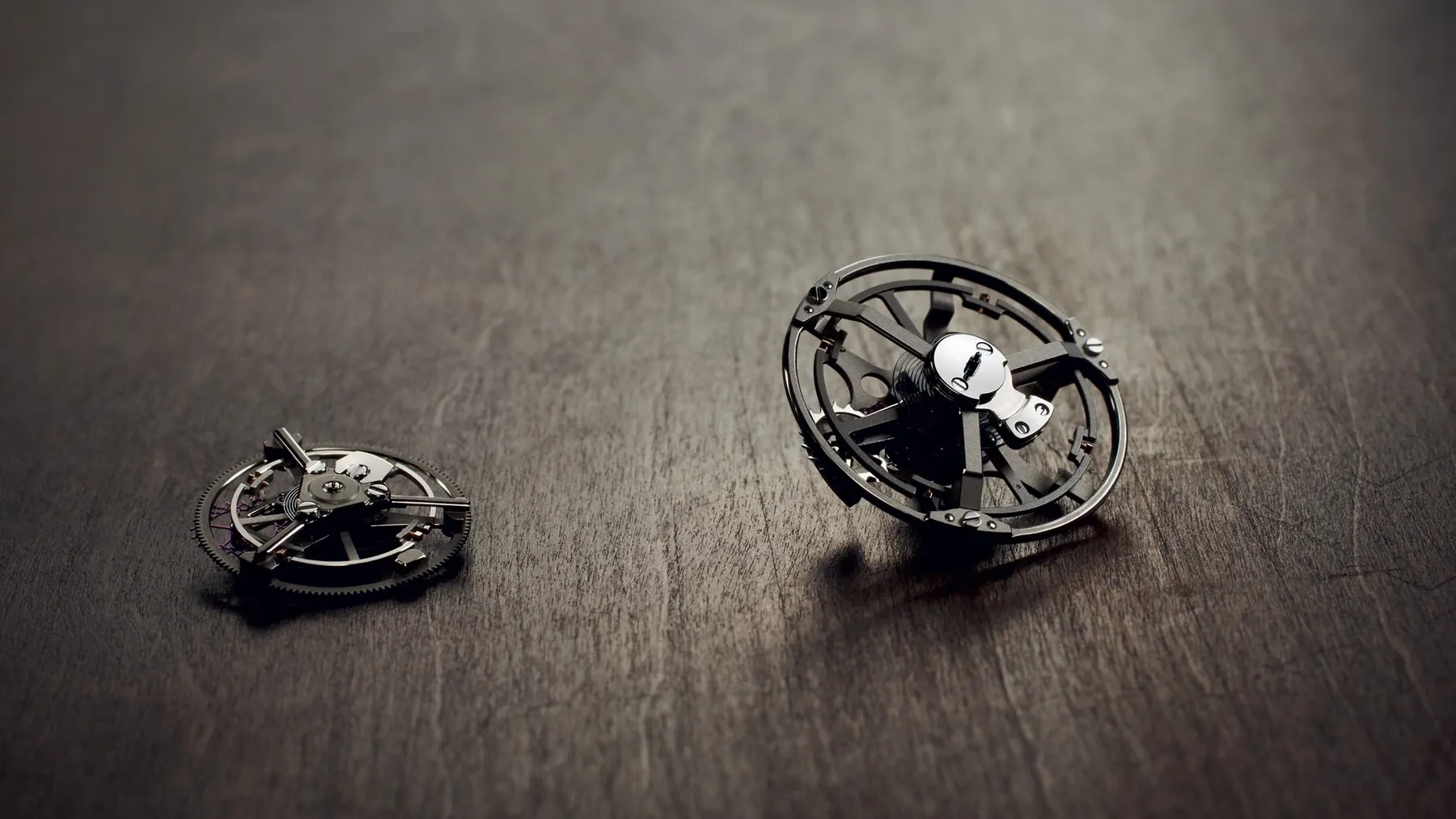 Két kiemelt Breguet tourbillon-egység egy műhelyfelületen, az eltérő méretű ketrecek és billegők összehasonlításához.